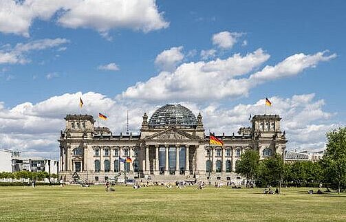 Außenansicht des Reichstags mit wehender Fahne und der Platz der Republik